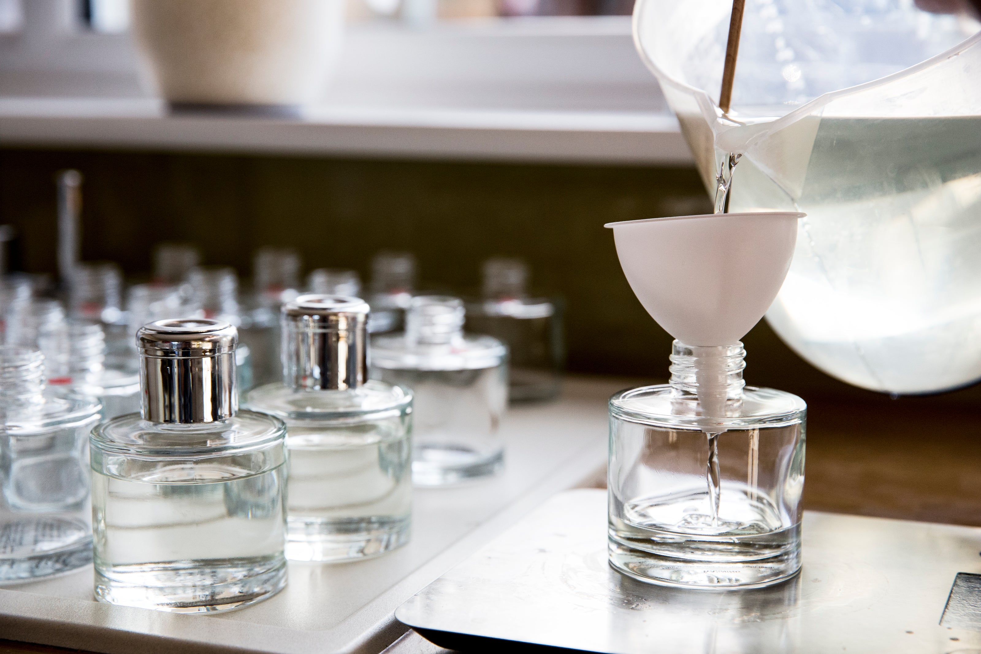 Fabrication artisanale de parfum d’ambiance – versement de la fragrance dans un flacon en verre, création d’une signature olfactive unique.